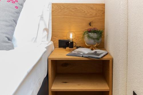 a nightstand next to a bed with a lamp and a plant at Hiša Križaj in Bohinj