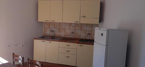 a kitchen with white cabinets and a white refrigerator at Il pergolato in Bari Sardo