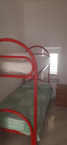 a red bunk bed in a room with a window at Il pergolato in Bari Sardo