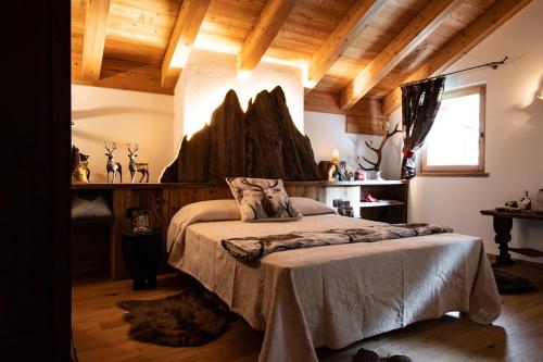 a bedroom with a bed in a room with wooden ceilings at Dolomiti Chalet degli Abeti in Campitello di Fassa