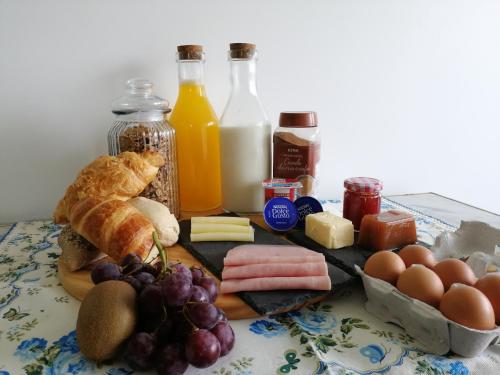 a table topped with cheese bread eggs meats and milk at Casa da Paraventa in Gaieiras