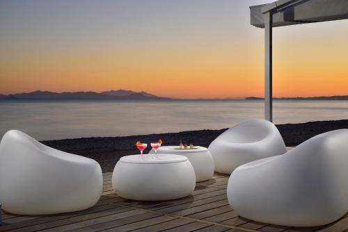 The Sense Experience Resort في فولونيكا: مجموعة من الكراسي البيضاء والطاولات على الشاطئ
