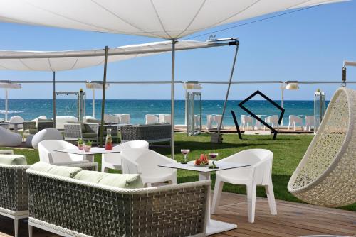 un patio con tavoli, sedie e spiaggia di The Sense Experience Resort a Follonica