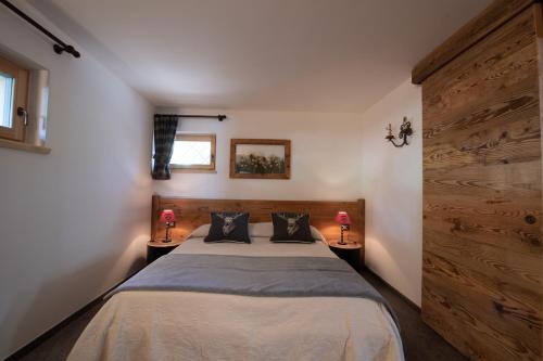 a bedroom with a bed and two lamps on two tables at Chalet degli Abeti by AMA Val di Fassa in Campitello di Fassa