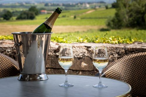 two glasses of white wine are sitting on a table at Hôtel Villa Alexandre in Régnié