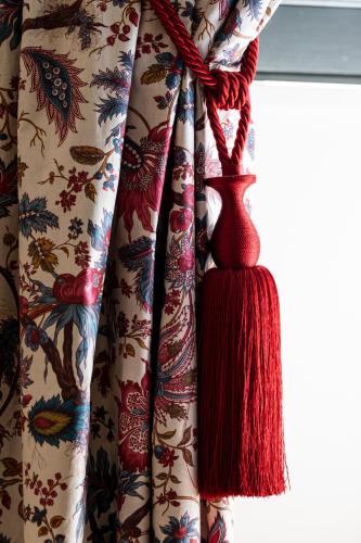 a curtain with a red tassle hanging from a window at Hôtel Villa Alexandre in Régnié