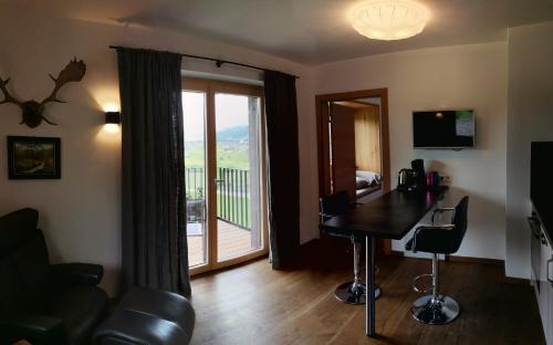 a living room with a table and a balcony at Gasthof Hubertus in Saalfelden am Steinernen Meer