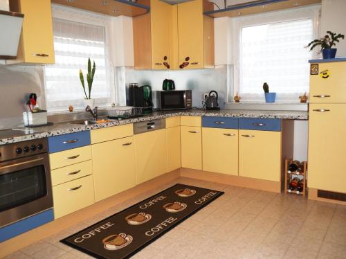 eine Küche mit gelben Schränken und einem Teppich auf dem Boden in der Unterkunft Ferienwohnung Leon in Kappel-Grafenhausen
