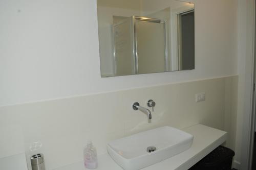 a white bathroom with a sink and a mirror at The Roof On The Sea in Fondachello