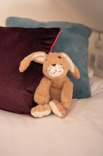 a stuffed rabbit sitting on a bed next to a pillow at Forty Winks Loch Lomond in Balloch