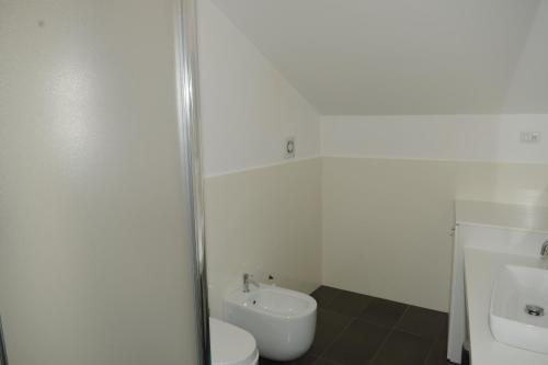 a white bathroom with a toilet and a sink at The Roof On The Sea in Fondachello