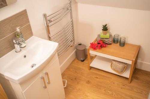 a bathroom with a sink and a table with flowers at Forty Winks Loch Lomond in Balloch