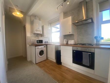 a kitchen with white cabinets and a washer and dryer at Coastal Corner in Mundesley