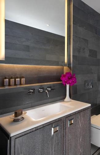 a bathroom with a sink and a vase of flowers at Flemings Mayfair - Small Luxury Hotel of the World in London