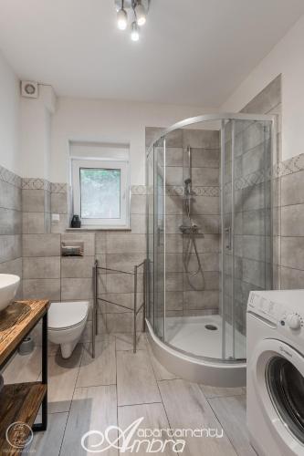 a bathroom with a shower and a toilet and a sink at Apartamenty Ambra in Dębina