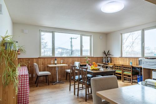 comedor con mesa, sillas y ventanas en Lodge Romulus en Rusutsu