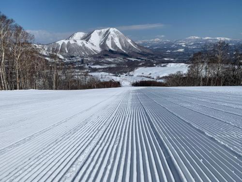 a snow covered road with a mountain in the background at Lodge Romulus in Rusutsu