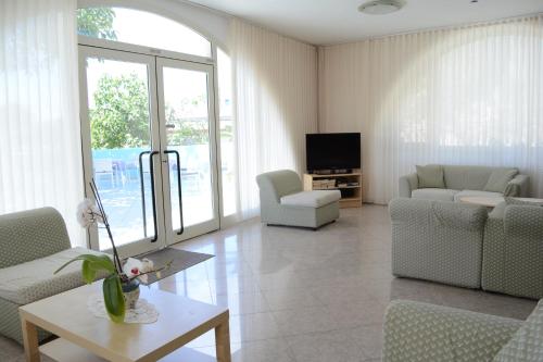 uma sala de estar com cadeiras, uma televisão e uma mesa em Hotel Maronti em Ischia