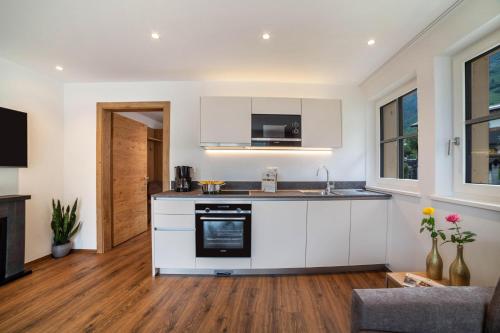 a kitchen with white cabinets and a stove at Engel Appartements Kirchturm in Parcines