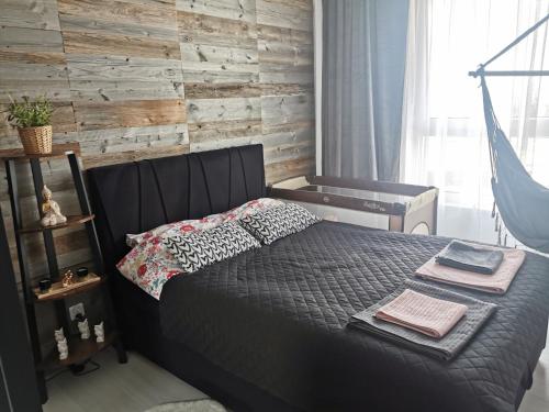 sypialnia z łóżkiem i drewnianą ścianą w obiekcie Apartament przy Bursztynowym Stadionie w Gdańsku