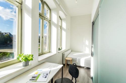 Habitación con cama, escritorio y ventanas. en Lofty Kampus Garnizon en Gdansk