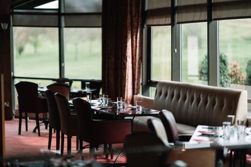 a dining room with tables and chairs and windows at Roe Valley Resort in Limavady
