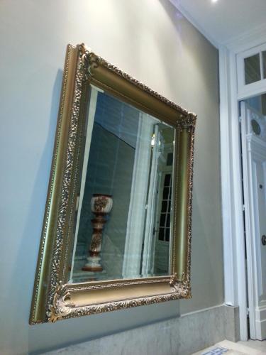 a gold framed mirror hanging on a wall at New Arapey Hotel in Montevideo