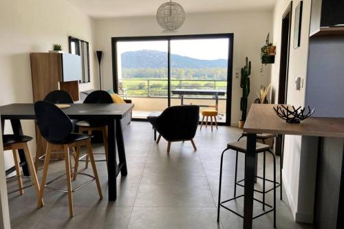un salon avec des chaises, des tables et une grande fenêtre dans l'établissement Appartement Stanatura - Luxe - Proche du port - 1 chambre - Pour des vacances paisibles, à Porto-Vecchio