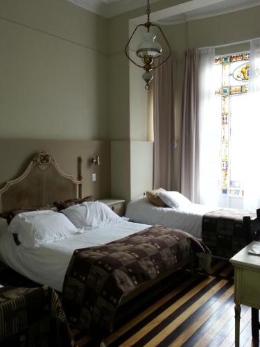 two beds in a bedroom with a window and a window at New Arapey Hotel in Montevideo