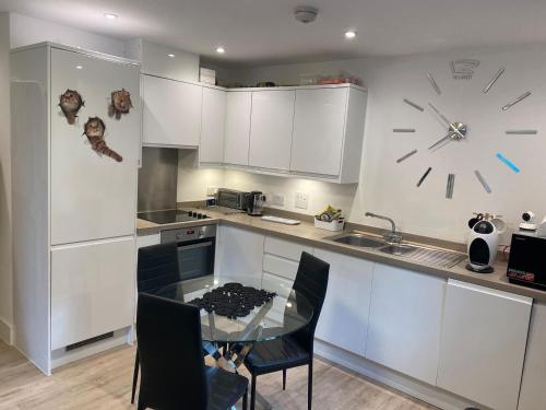 a kitchen with a table and a clock on the wall at Ashs Apartments in Southampton