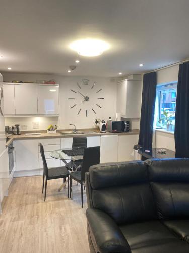 a living room with a table and a clock on the wall at Ashs Apartments in Southampton