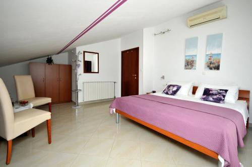 a bedroom with a large bed and a chair at Apartments Roza in Trogir