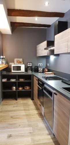 una cucina con elettrodomestici in acciaio inossidabile e mobili in legno di Lodge-Sagne une ferme rénovée au cœur du Cantal à proximité de la station de ski du Lioran a Neussargues en Pinatelle