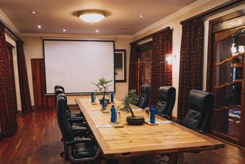 a conference room with a table and chairs and a screen at Kleinkaap Boutique Hotel in Centurion