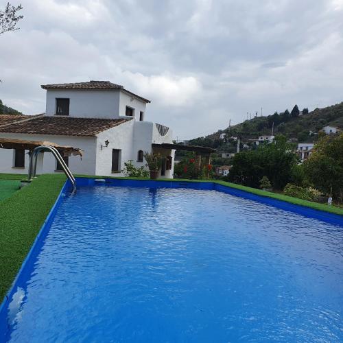 a large blue swimming pool in front of a house at Casa del rio in Málaga