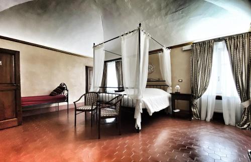 a bedroom with a canopy bed and a chair at Abbazia delle Sorelle in Novello