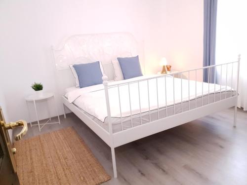 a white bed with blue pillows in a bedroom at Eva Home in Roşiori de Vede