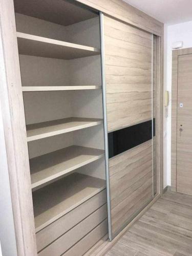 a closet with wooden shelves and a glass door at Apartment La Gavina Beach Barcelona Airport in Gavà