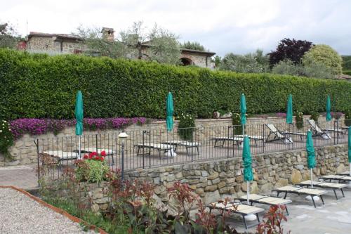 a stone wall with tables and chairs and umbrellas at Agriturismo Annibale in Tuoro sul Trasimeno