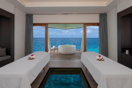 two beds in a room with a view of the ocean at Radisson Blu Resort Maldives with 50 percent off on Sea Plane round trip 03 nights & above in Fenfushi