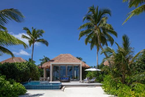 a resort with a swimming pool and palm trees at Radisson Blu Resort Maldives with 50 percent off on Sea Plane round trip 03 nights & above in Fenfushi