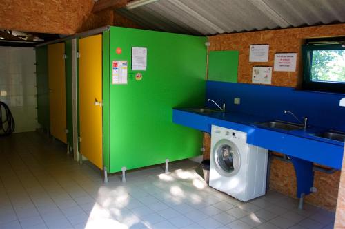 a bathroom with a washing machine and a green wall at camping de la chagnée in Saint-Aubin-le-Cloud