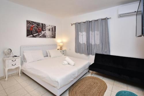 a small bedroom with a white bed and a couch at וילה גאיה בכנרת-VIILA GAYA in Migdal