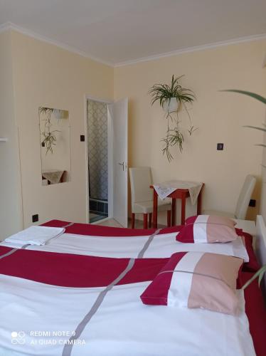 a bedroom with a large bed with red and white sheets at Akác Vendégház in Eger