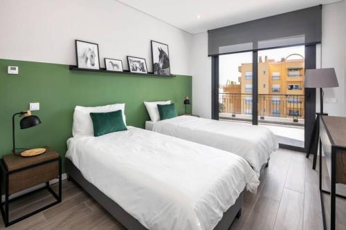Duas camas num quarto com uma parede verde em Apartment Confort 404 em Portimão