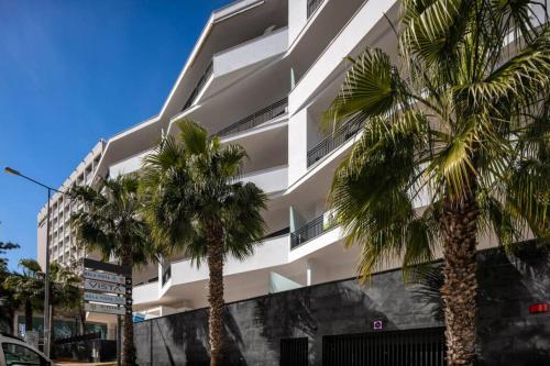 a white building with palm trees in front of it at Apartment Confort 404 in Portimão