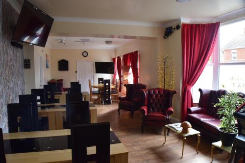 ein Wohnzimmer mit roten Stühlen, einem Sofa und einem Tisch in der Unterkunft Seashells Beach Hotel in Sutton on Sea