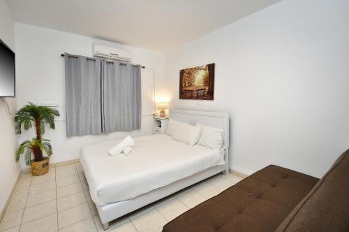 a white bed in a room with a couch at וילה גאיה בכנרת-VIILA GAYA in Migdal
