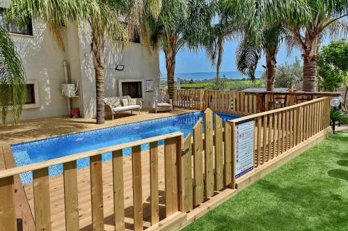 a wooden fence around a swimming pool with palm trees at וילה גאיה בכנרת-VIILA GAYA in Migdal
