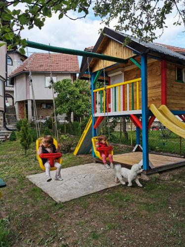 two children playing on a swing set with a dog at Apartman Jela in Nova Varoš